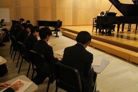 大学生のピアノ演奏を鑑賞する生徒<br>（ピアノ実習）