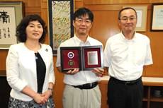 記念の盾を手に後藤学長，菅沼副学長と歓談する高橋教授