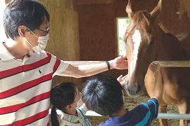 馬の頬をなでる家族