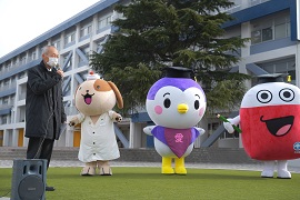 あいさつをする野田敦敬学長と本学のマスコットキャラクター