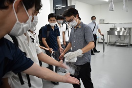 施設見学で、科学実験のデモンストレーションを体験する高校生