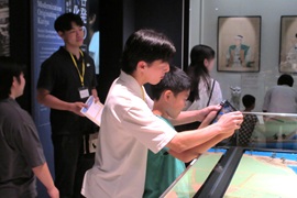 大学院生と一緒にタブレット端末を使ってジオラマを見る児童