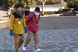 本学職員OB柳田芳久さん（右）と歓談しながら歩く学長（左）