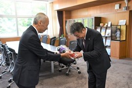 野田敦敬学長から佐野智正氏へ記念品（マスコットキャラクター）を贈呈
