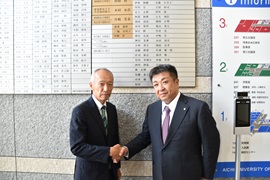 銘板の前で野田学長と握手する佐野氏