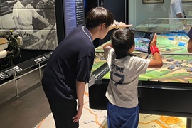 タブレット端末を使ってジオラマを見る児童