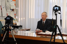 カメラの前で子どもたちへのメッセージを話す野田敦敬学長