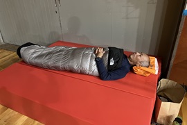 災害用マットレス上で寝袋体験をする野田学長