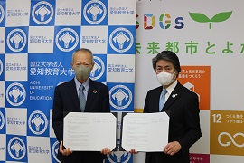 協定書を掲げる野田学長（左）と太田市長（右）
