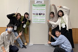 実践発表のポスターを背景に参加した学生で記念写真