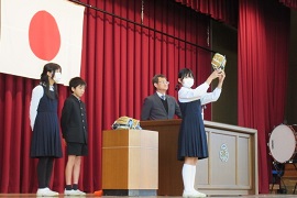 全校集会でグローブを掲げる附属岡崎小学校の児童