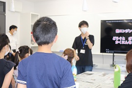 鈴木俊彦さん（技術専攻4年）の説明を聞く子どもたち