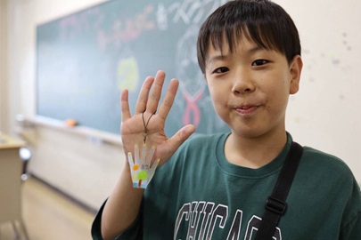 プラ板キーホルダーを持って微笑む小学生