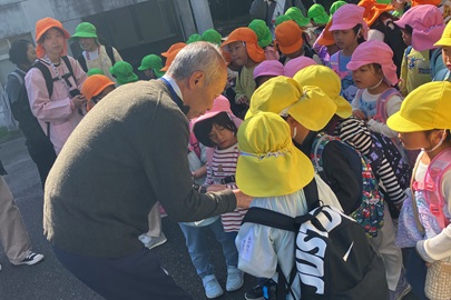 愛教ちゃんとエディにも会いに来てね！と、シールを渡す野田学長